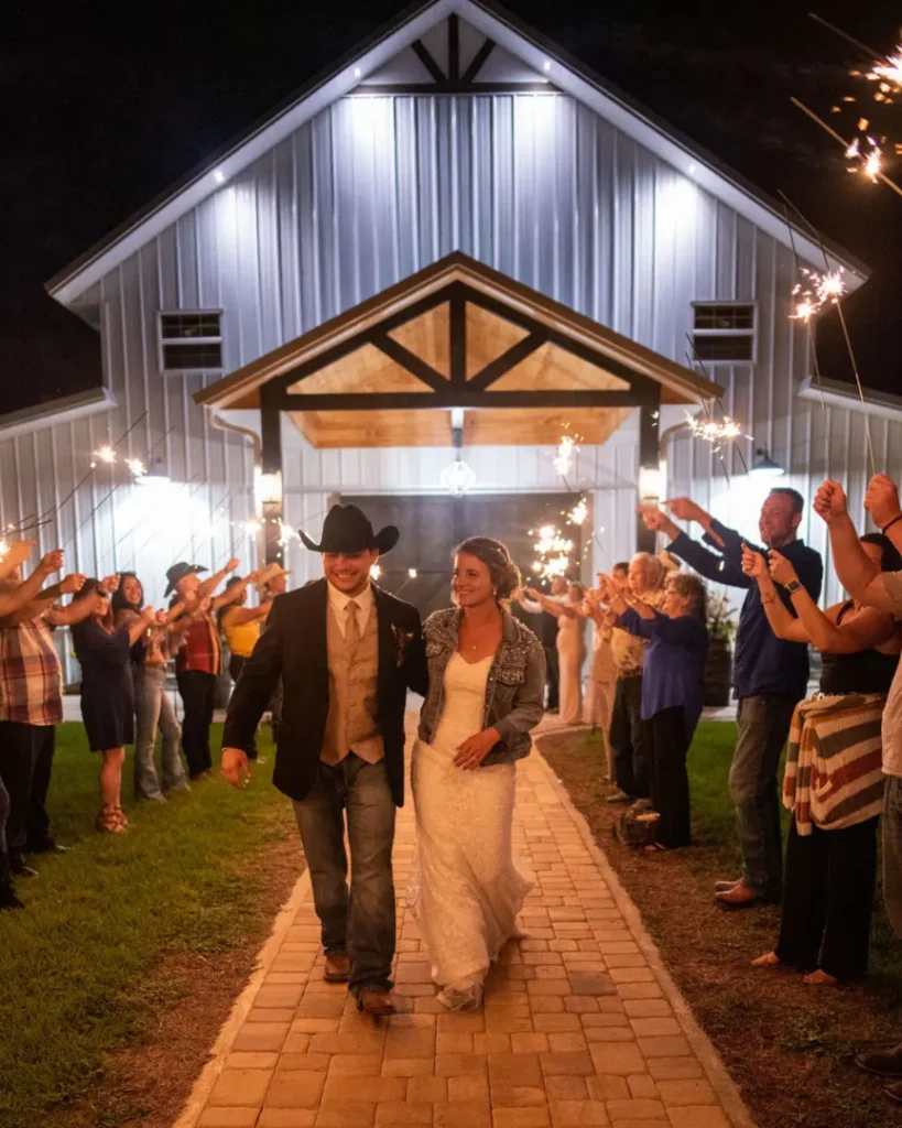 Bride and groom holding hands during a sparkler exit at an outdoor barn wedding reception at Legacy at Oak Meadows